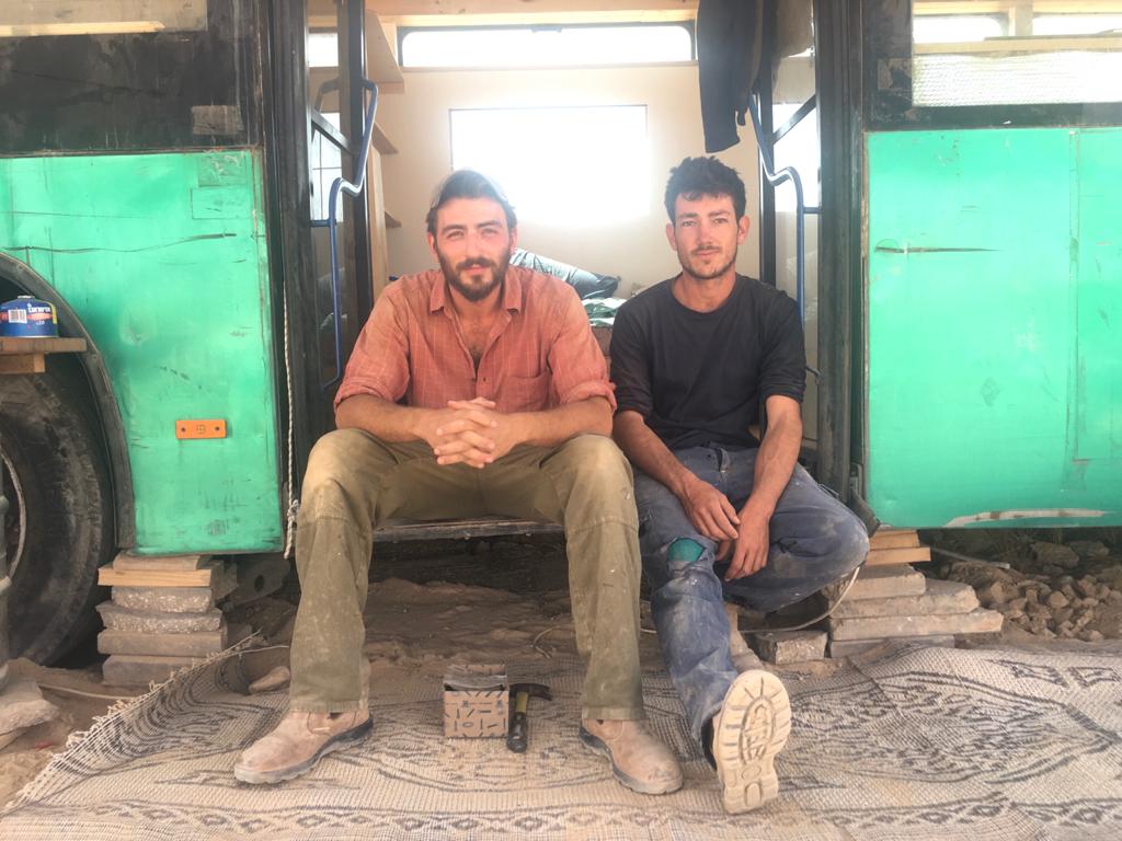 יותם ואריאל, מקימי אוטובוס בכרם, יושבים מול האוטובוס הירוק